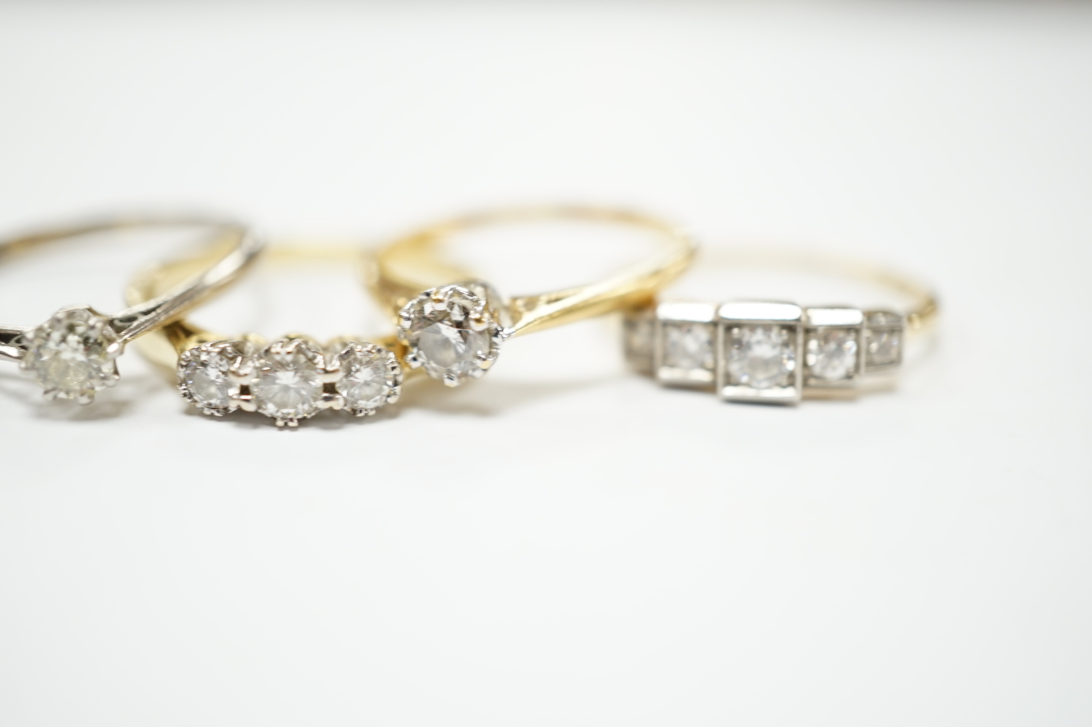 Four assorted 18ct and diamond set rings including a graduated five stone, three stone and two solitaires, gross weight 10.3 grams.